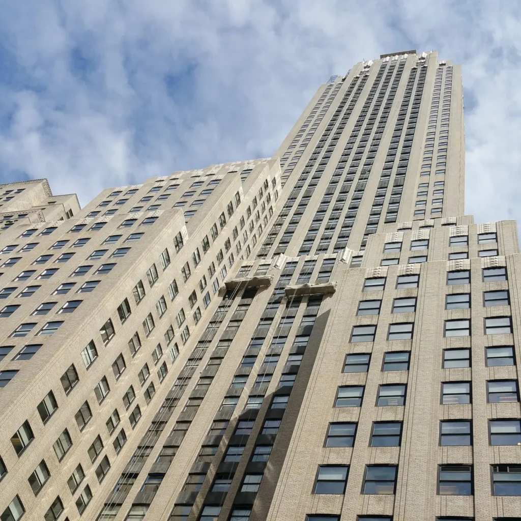 Tall skyscraper under blue sky representing ethical real estate investments.
