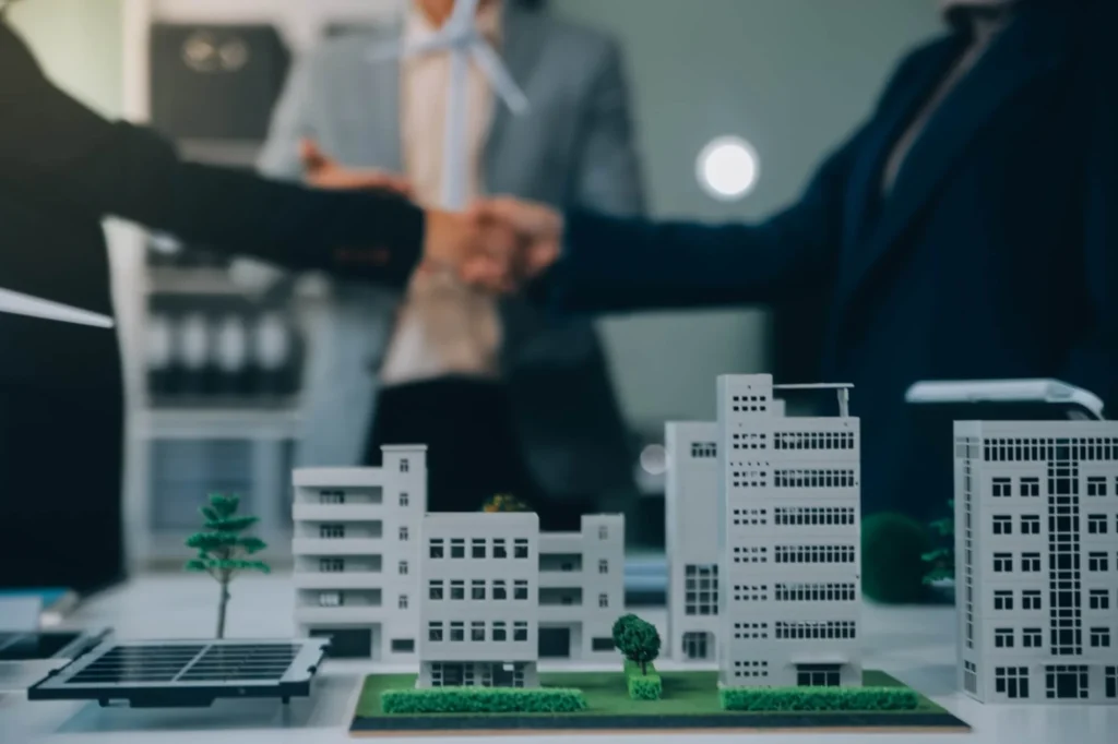 Model buildings on table as business professionals discuss Tawakkul REIT options.